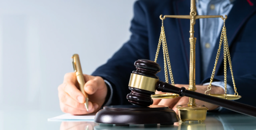 A judge writing on paper next to a gavel.